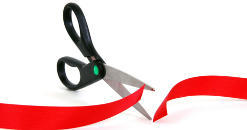Open scissors cutting through red tape