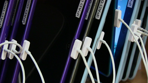 Row of iPads with numbered labels, all connected via 30-pin USB cables